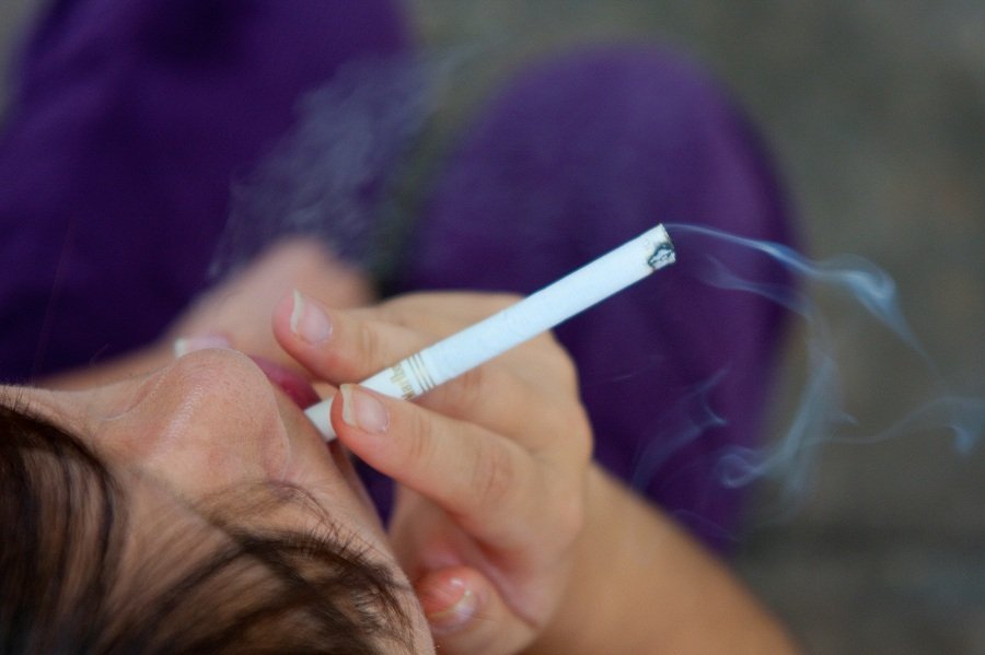 Imagem colorida de pessoa vista de cima ao fumar cigarro industrial - Metrópoles