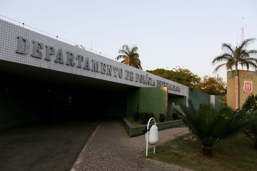Prédio com a sigla DPE e uma lixeira branca na frente
