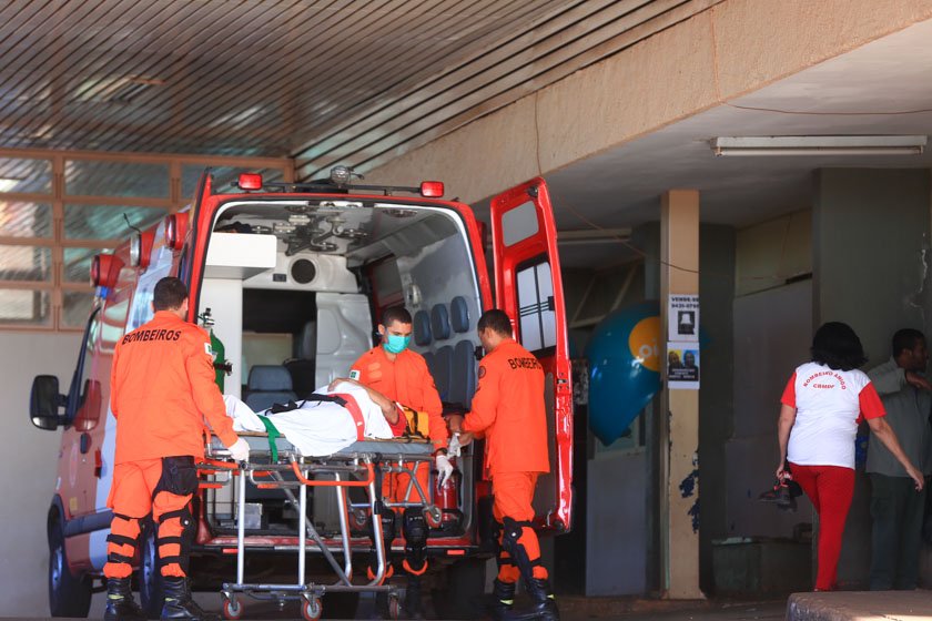 Bombeiros colocando pessoa em maca dentro de ambulância