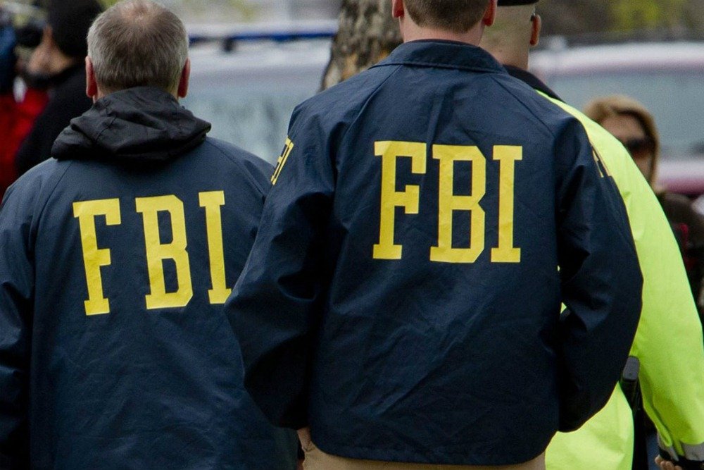 foto colorida de dois homens com jaqueta do FBI