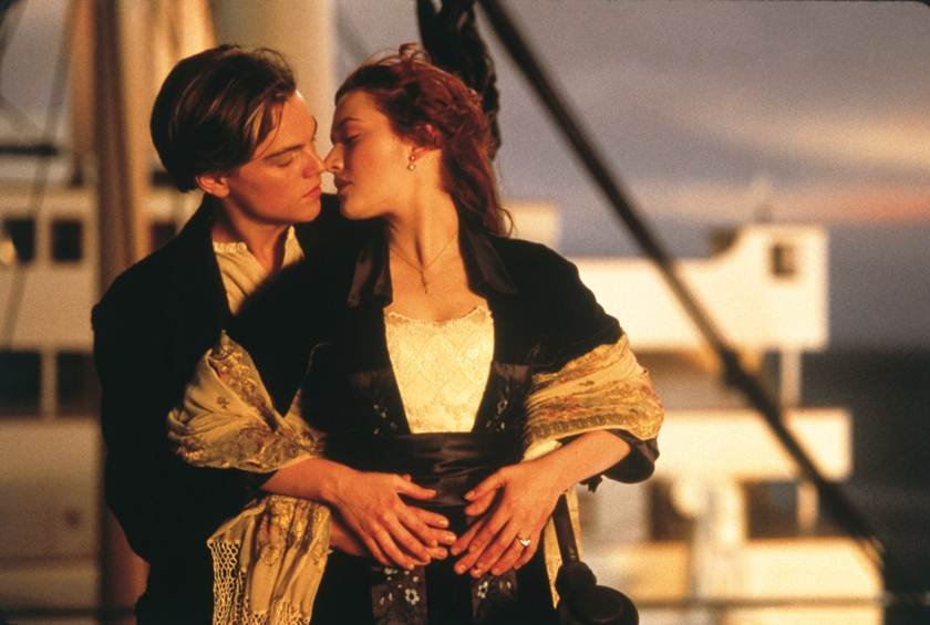 Cena do filme Titanic, com Leonardo DiCaprio e Kate Winslet. Ela é branca, ruiva e está com uma roupa preta e branca. Ele é branco, tem cabelo preto e está utilizando uma roupa preta - Metrópoles