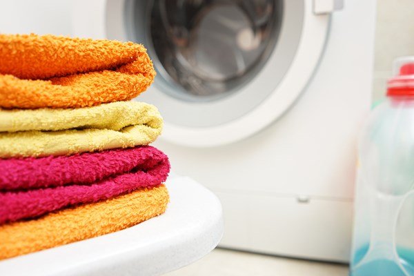 washed towels stacked with washing machine in background