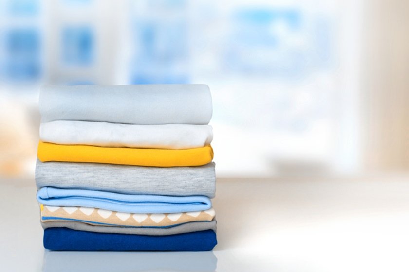 Stack cotton folded clothes on table indoors empty space.