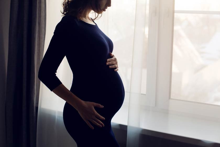 young pregnant girl in a blue bodycon dress standing