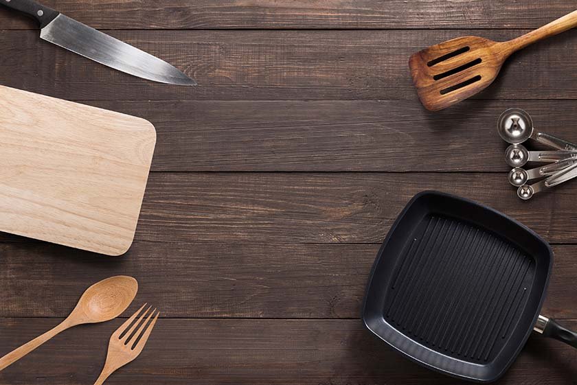 Various kitchenware utensils on the wooden background.