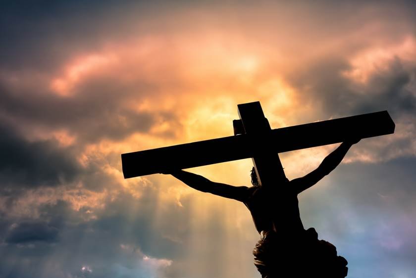 Christian cross with Jesus Christ statue over stormy clouds