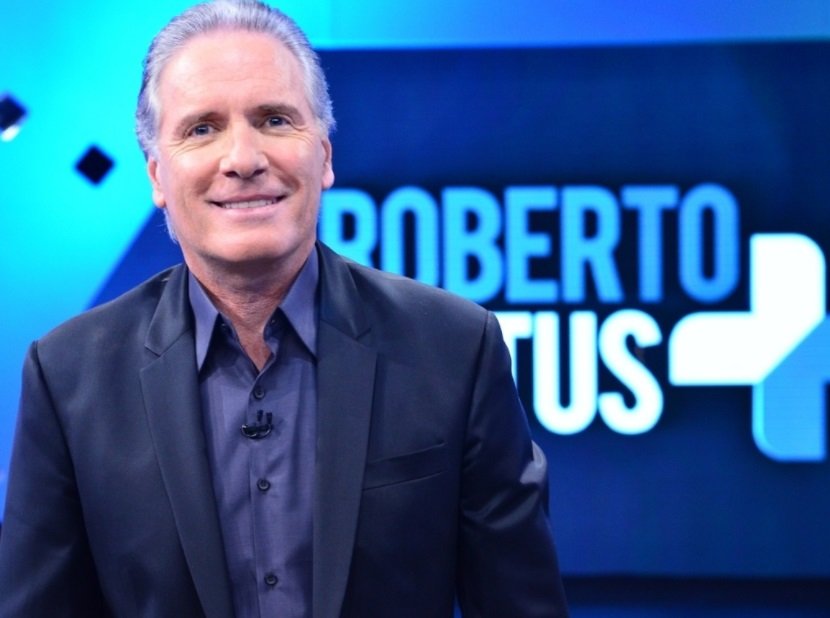 Foto colorida de Roberto Justus sorrindo e apresentando programa - Metrópoles