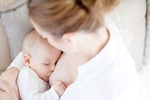 Foto colorida de mãe amamentando bebê - Metrópoles