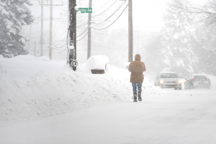 A resident walks north on Pine Ave as more snow falls after two days of record-breaking snowfall in Erie
