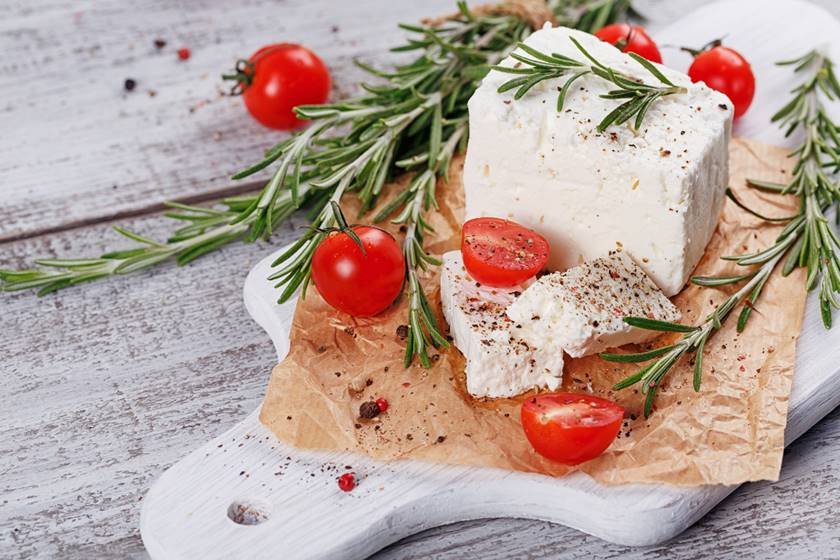 Fresh feta cheese with rosemary on white wooden serving board