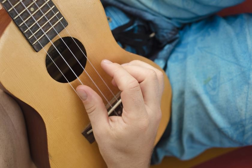 Detail of man relaxing on a hammock and playing ukulele