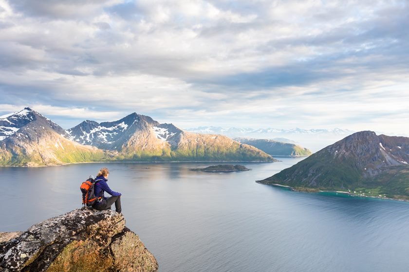 Woman hiker looking at a beautiful Norwegian Fjord landscape