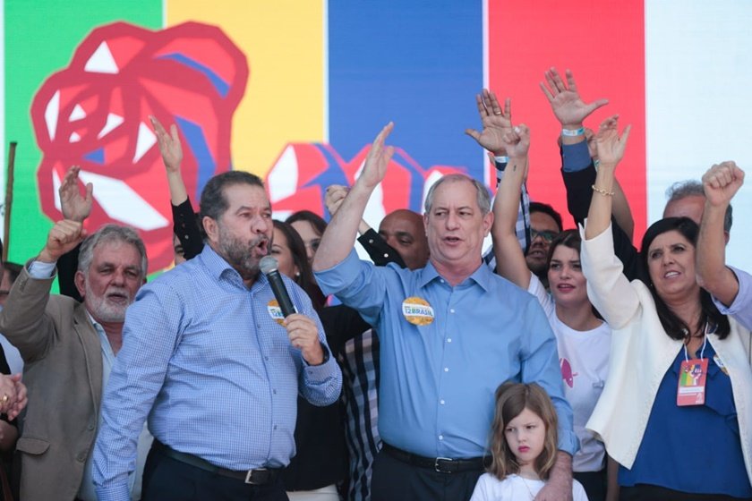 Ciro Gomes é oficializado pelo PDT como candidato a presidência ao lado do presidente da legenda, Carlos Luppi, que discursa no microfone. Eles estão rodeados por partidários com símbolos do partido ao fundo - Metrópoles