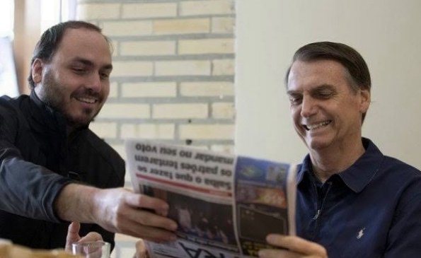 Carlos e Jair Bolsonaro lendo jornal