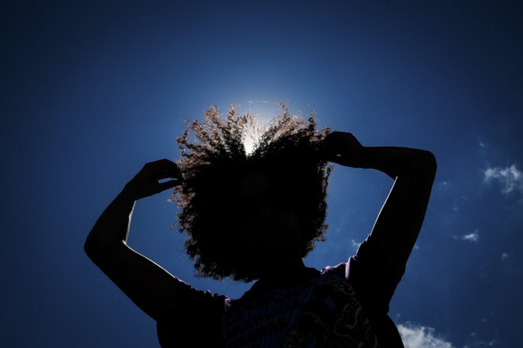 Silhueta de mulher negra com as mãos em cabelo crespo