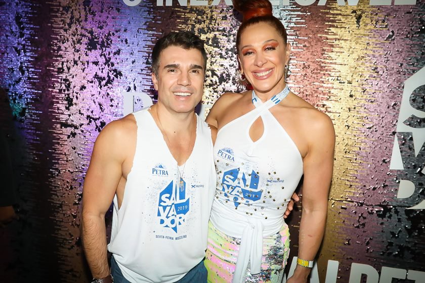 Jarbas Homem de Mello e Claudia Raia. Ele tem pele clara, cabelo curto e preto e usa uma regata branca. Ela usa um vestido branco, está de cabelo castanho escuro preso e tem pele clara. Os dois estão sorrindo- Metrópoles
