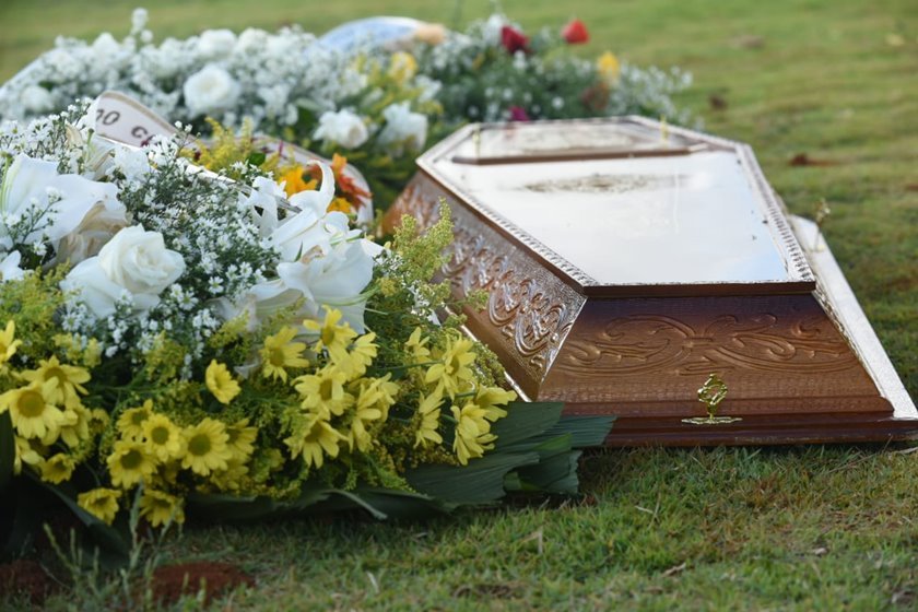 Coroa de flores e caixão em cemitério