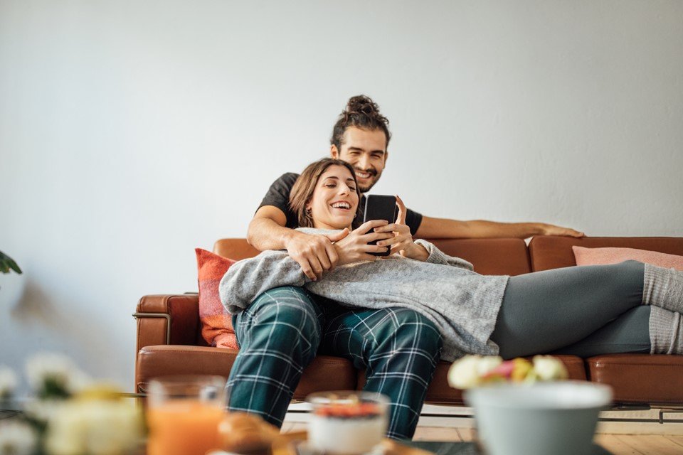 Young couple with smart phone relaxing on sofa