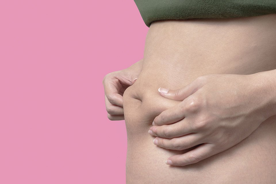 Fotografía en color de una mujer sosteniendo su estómago