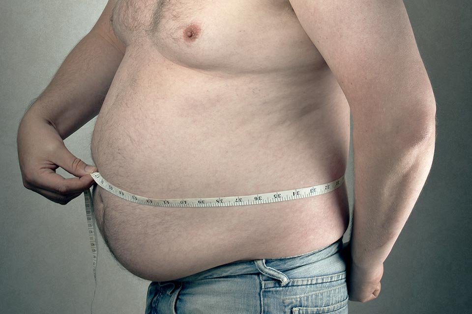 Imagem de homem com sobrepeso medindo a barriga com fita métrica - Metrópoles