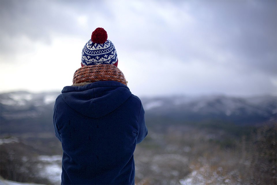 Mulher contempla paisagem no frio