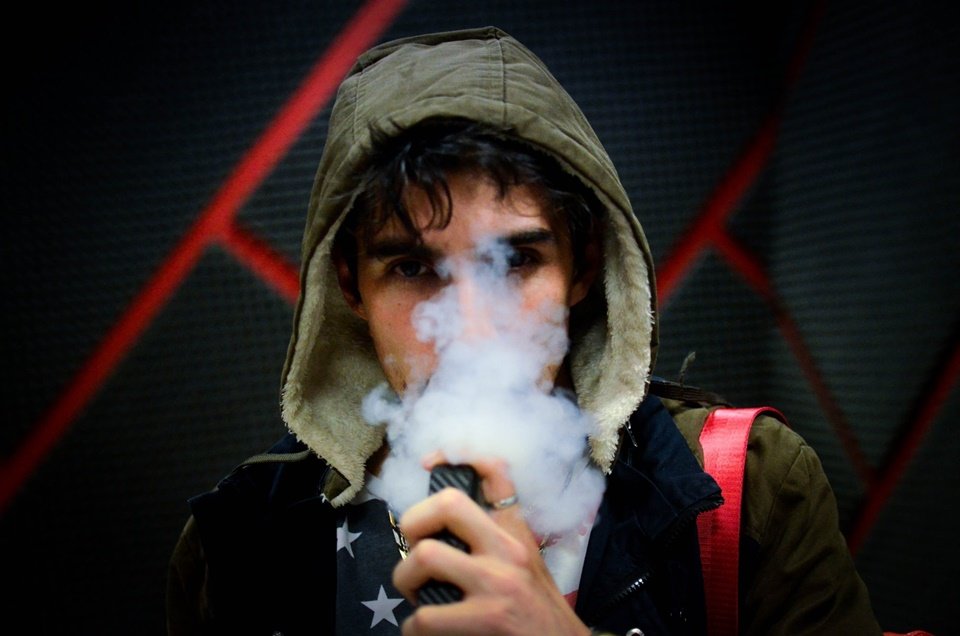 Jovem de capuz usando cigarro eletrônico - Metrópoles