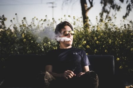 homem sentado fumando cigarro eletrônico, colorida
