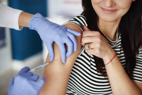 Fotografia colorida de mulher sendo vacinada
