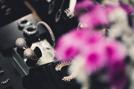 Anéis pratas em plataforma preta e flores roxas desfocadas ao lado direito
