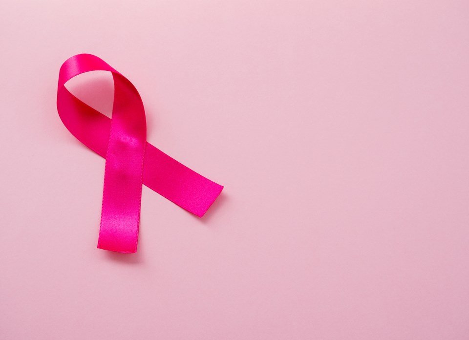 A pink ribbon on a pastel pink background. Breast cancer concept