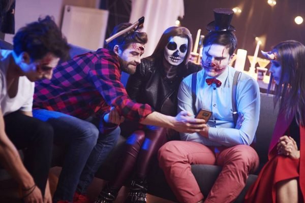 Friends using mobile phone at Halloween party
