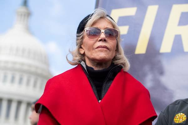 Foto colorida da atriz Jane Fonda usando blusa vermelha e óculos escuros - Métropoles