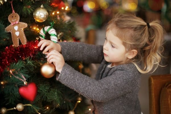 A little girl holding a Christmas tree bauble