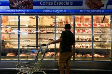 Consumidor observa mostruário de carnes em um mercado