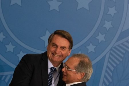 Jair Bolsonaro e Paulo Guedes se abraçam sorrindo