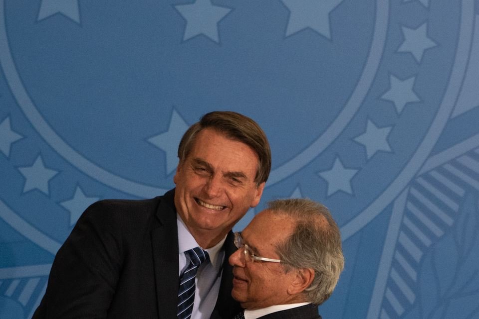 Jair Bolsonaro e Paulo Guedes se abraçam sorrindo