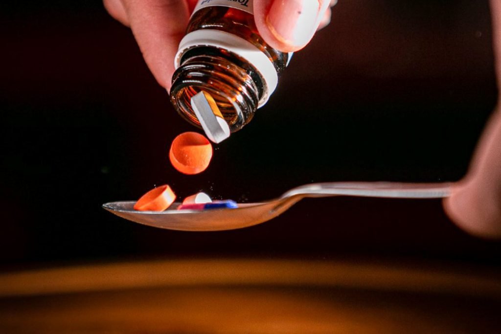 Color photograph of medicine falling into a spoon