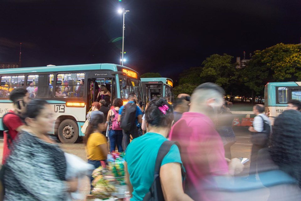 Movimentação de pessoas andando e ônibus ao fundo