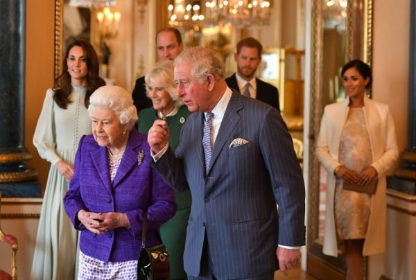 Fotografia colorida.  O príncipe Charles aparece à direita da imagem andando com a mãe, rainha Elizabeth II no palácio