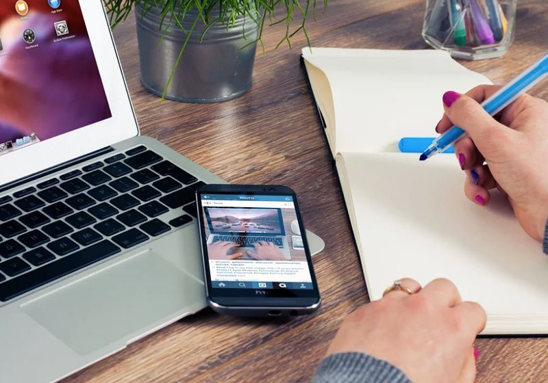 Celular, bloco de papel, computador e home office