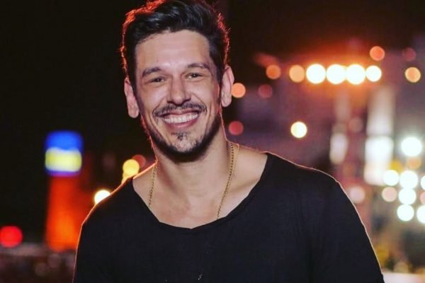Foto colorida de João Vicente de Castro sorrindo e usando camiseta preta - Metrópoles