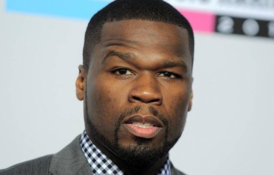 Foto do cantor 50 Cent. Ele é um homemnegro, com cabelo curto, barba preta e está de terno cinza - Metrópoles