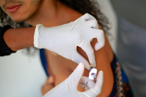 vacina sendo aplicada em braço de paciente