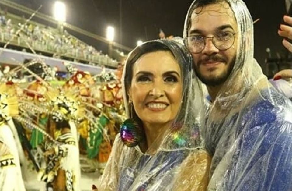 Com chuva, Fátima Bernardes e Túlio curtem desfile agarradinhos