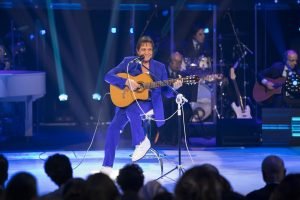 Rei Roberto Carlos cantando e tocando violão em palco