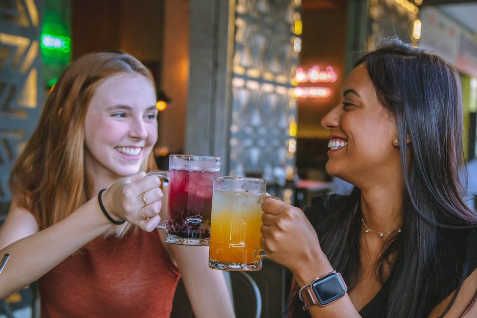 Mulheres brindam com refrescos na hamburgueria O Concorrente