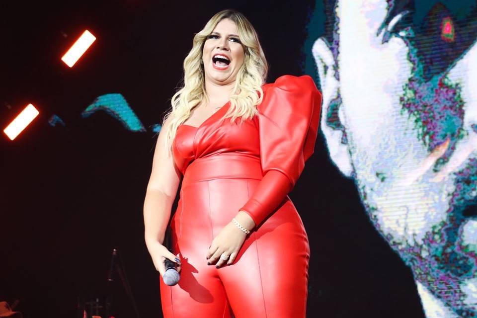 Marília Mendonça de macacão vermelho em show na cidade de São Paulo