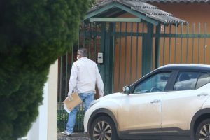 Oficial de Justiça, com máscara, tenta falar com marido de paciente que tem coronavírus