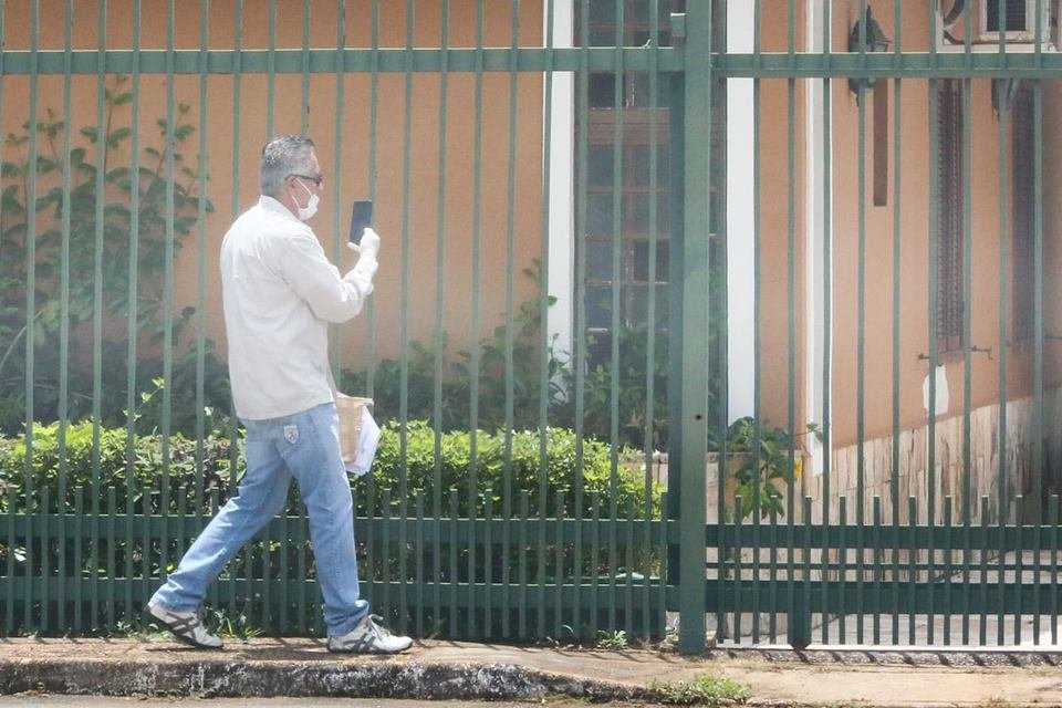 Oficial de Justiça, com máscara, tenta falar com marido de paciente que tem coronavírus