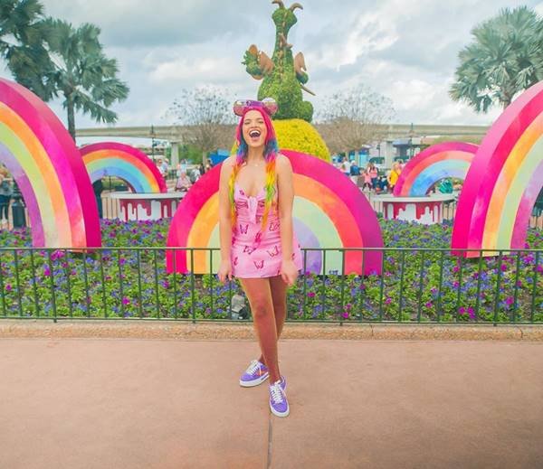 anna-layza-em-frente-a-jardim-com-arco-iris